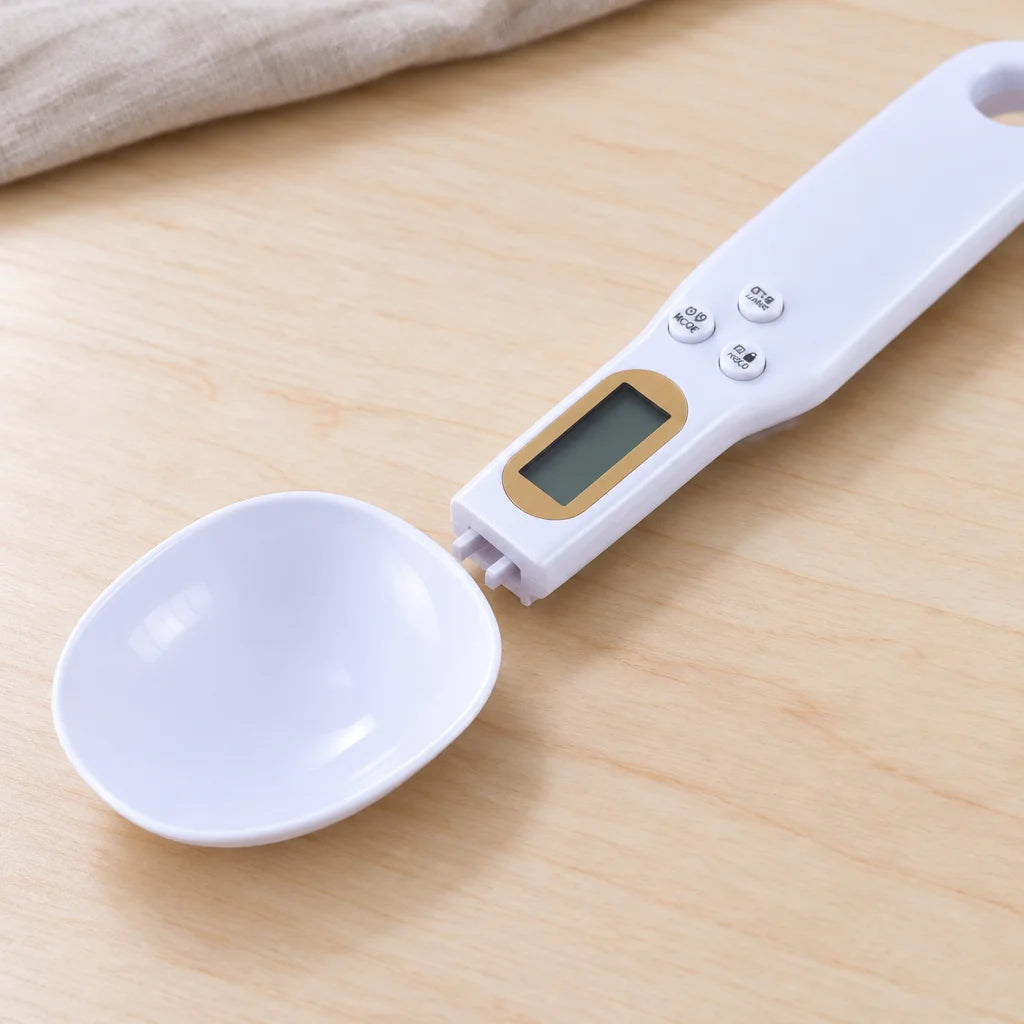 A close macro kitchen photograph of the white Doseo digital spoon scale with its removable spoon bow