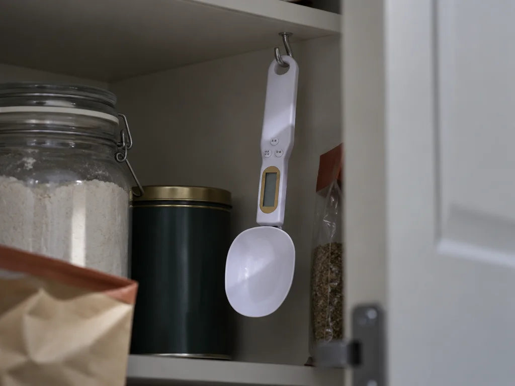 A photograph of the exact white digital weighing spoon from the supplied reference hanging by the ro